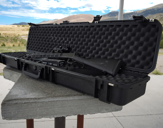 Valise rigide SKB ouverte avec mousse alvéolée dans le couvercle et le fond, contenant du matériel rangé, posée sur une surface en béton dans un environnement extérieur.