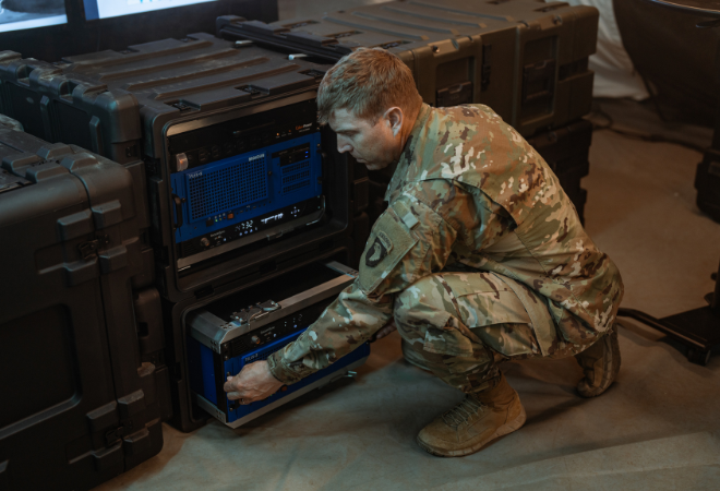 Un collaborateur militaire travaille sur un rack SKB ouvert de 19 pouces avec électronique intégrée, entouré de plusieurs racks SKB fermés de 19 pouces dans un environnement opérationnel.
