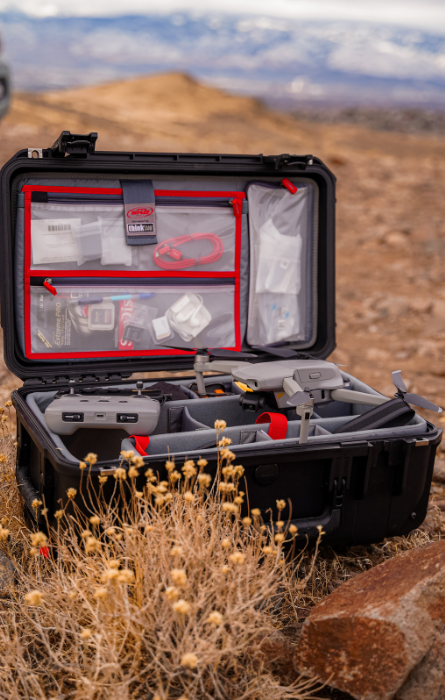 Valise SKB noire ouverte avec compartiments organisés et accessoires, utilisée pour stocker et transporter en toute sécurité un drone et son équipement dans un environnement extérieur.