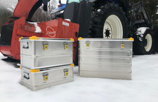 Caisses en aluminium Viking dans la neige, placées à côté d'une machine agricole