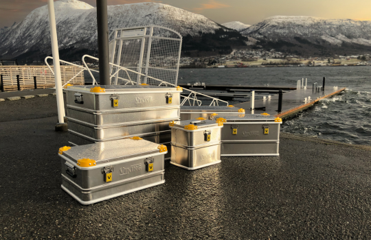 Caisses en aluminium Viking sur un quai au bord de l'eau, avec un paysage montagneux en arrière-plan